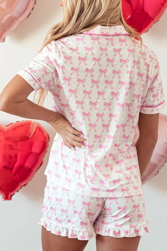 Woman wearing pink and white bow patterned two-piece lounge set with frilled shorts and short-sleeve shirt