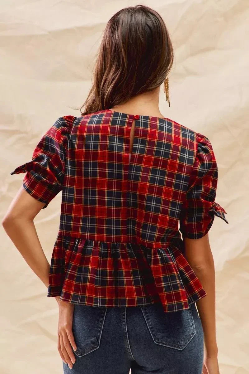 Back view of a woman wearing a Christmas holiday plaid ribbon short sleeves top with ruffled hem and tied sleeves