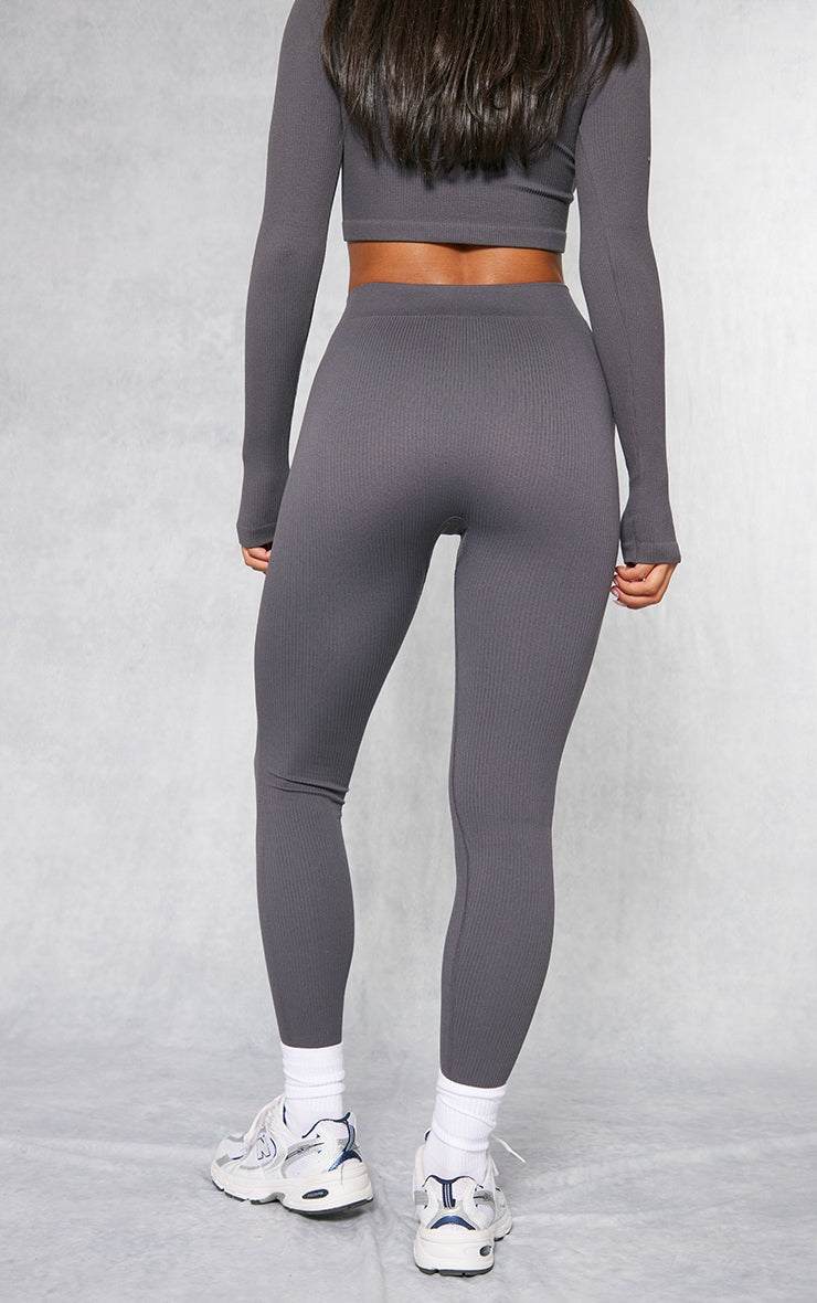 Black structured contour ribbed leggings with a fitted silhouette and high waist, styled with white sneakers and a matching cropped top