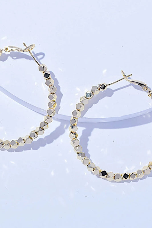 Pair of gold-tone alloy hoop earrings with geometric faceted design, 2.4 inches long.