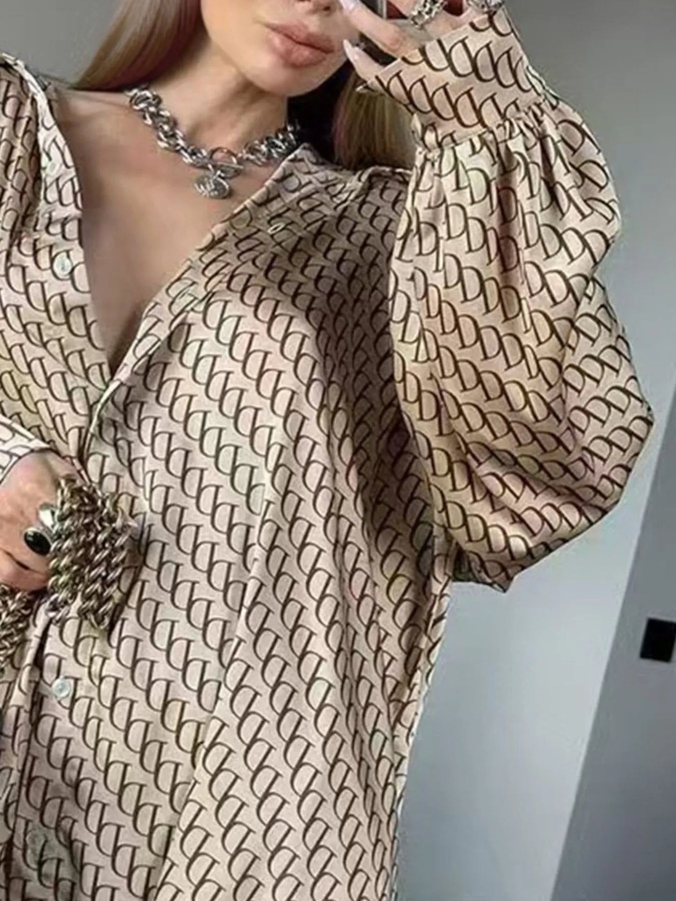 Close-up of woman wearing oversized printed button up shirt with beige and brown pattern and gathered cuffs