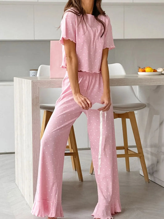 Woman wearing pink polka dot round neck top and pants lounge set with ruffled edges