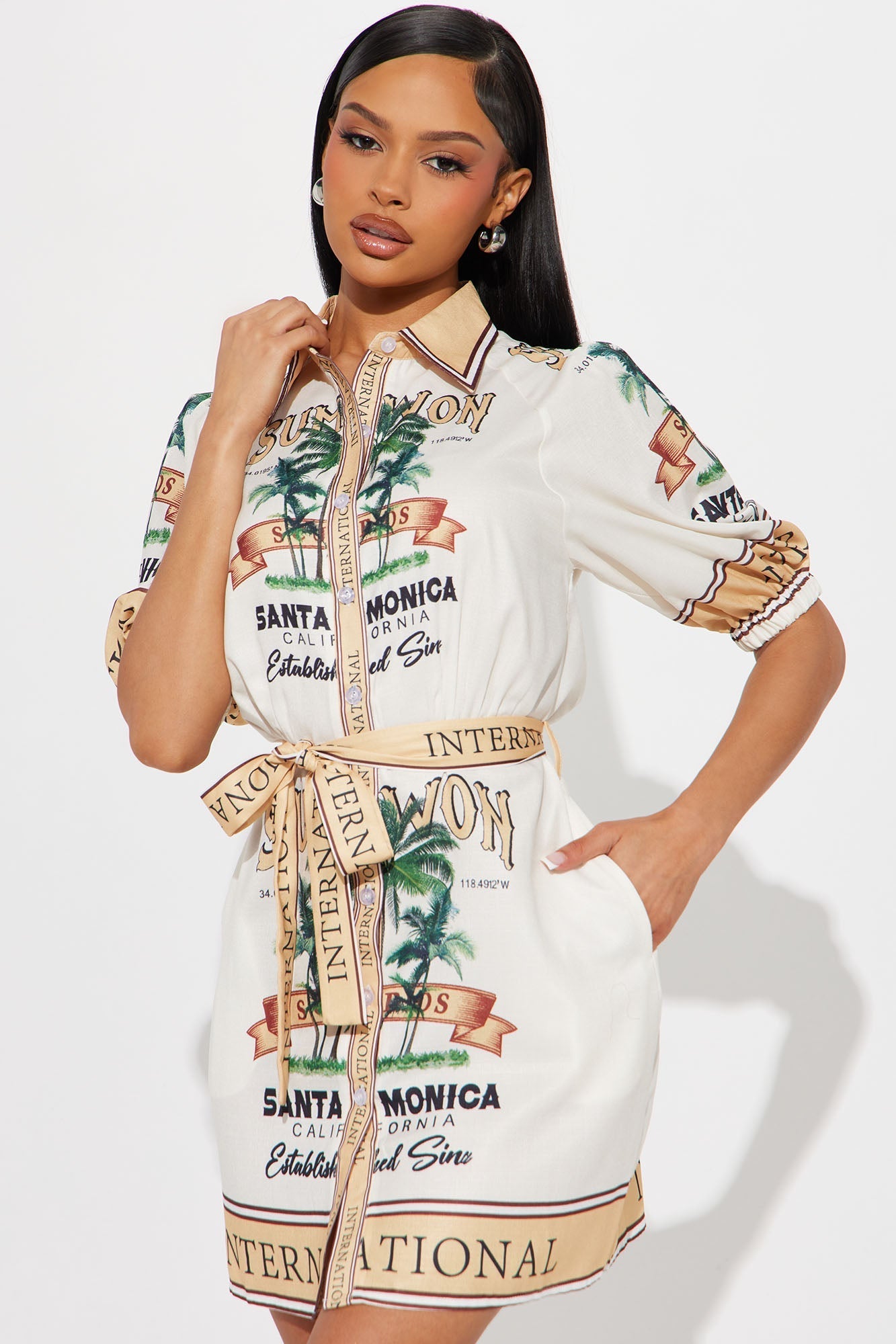 Woman wearing Santa Monica Satin Shirt Mini Dress in gold combo with palm tree print and tie front