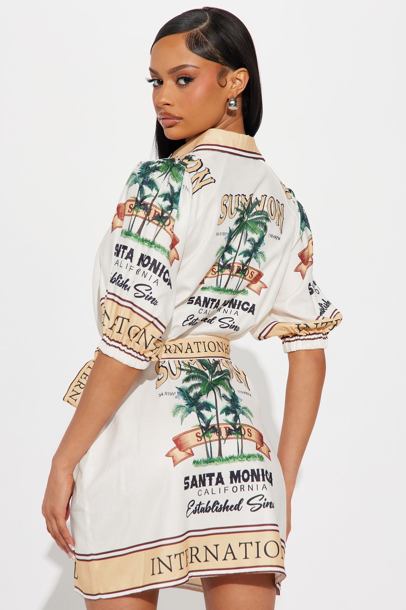 Woman wearing Santa Monica Satin Shirt mini dress with palm tree print and tie front in gold/combo colors
