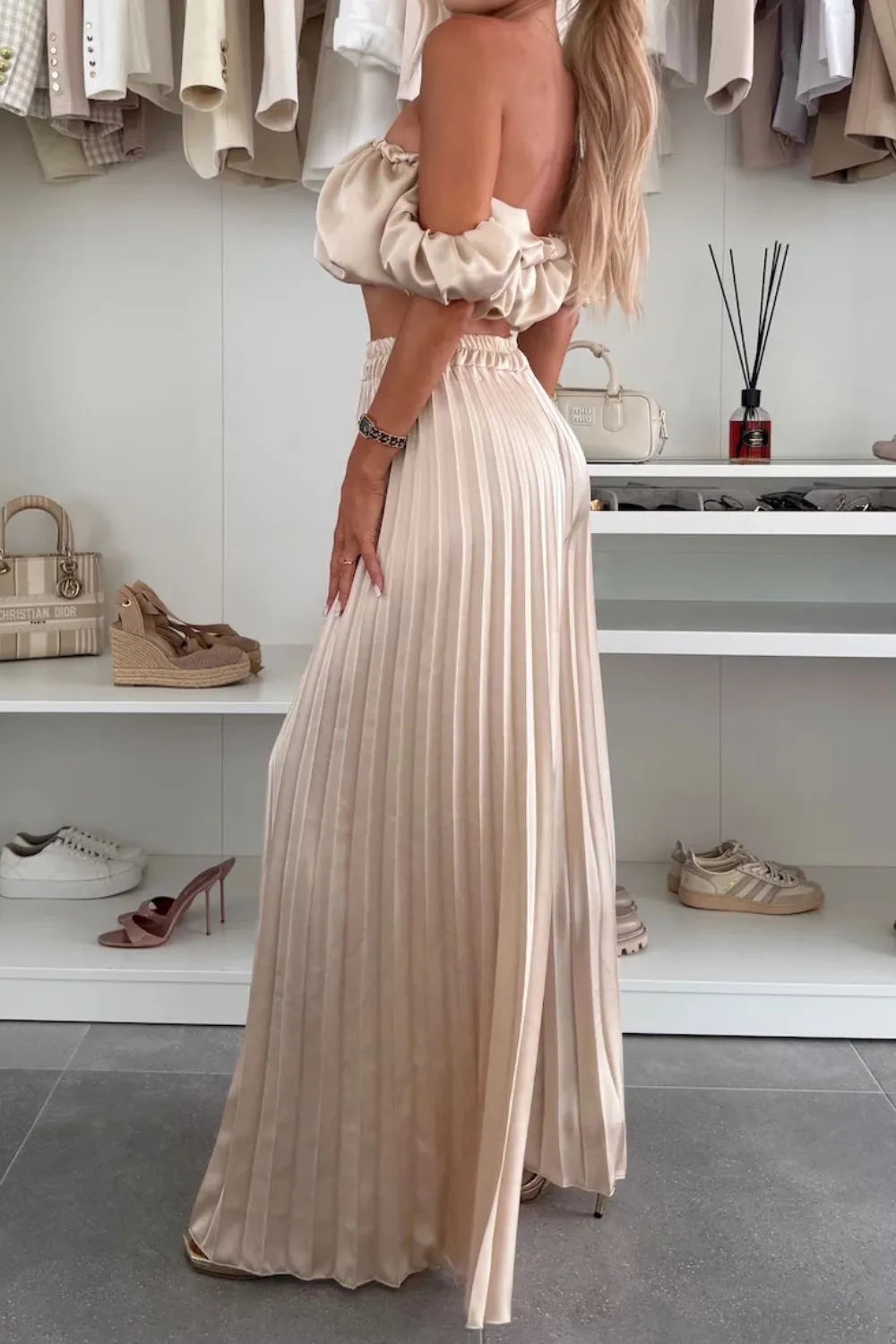 Woman wearing cream off-shoulder ruffled top and pleated pants set in polyester fabric