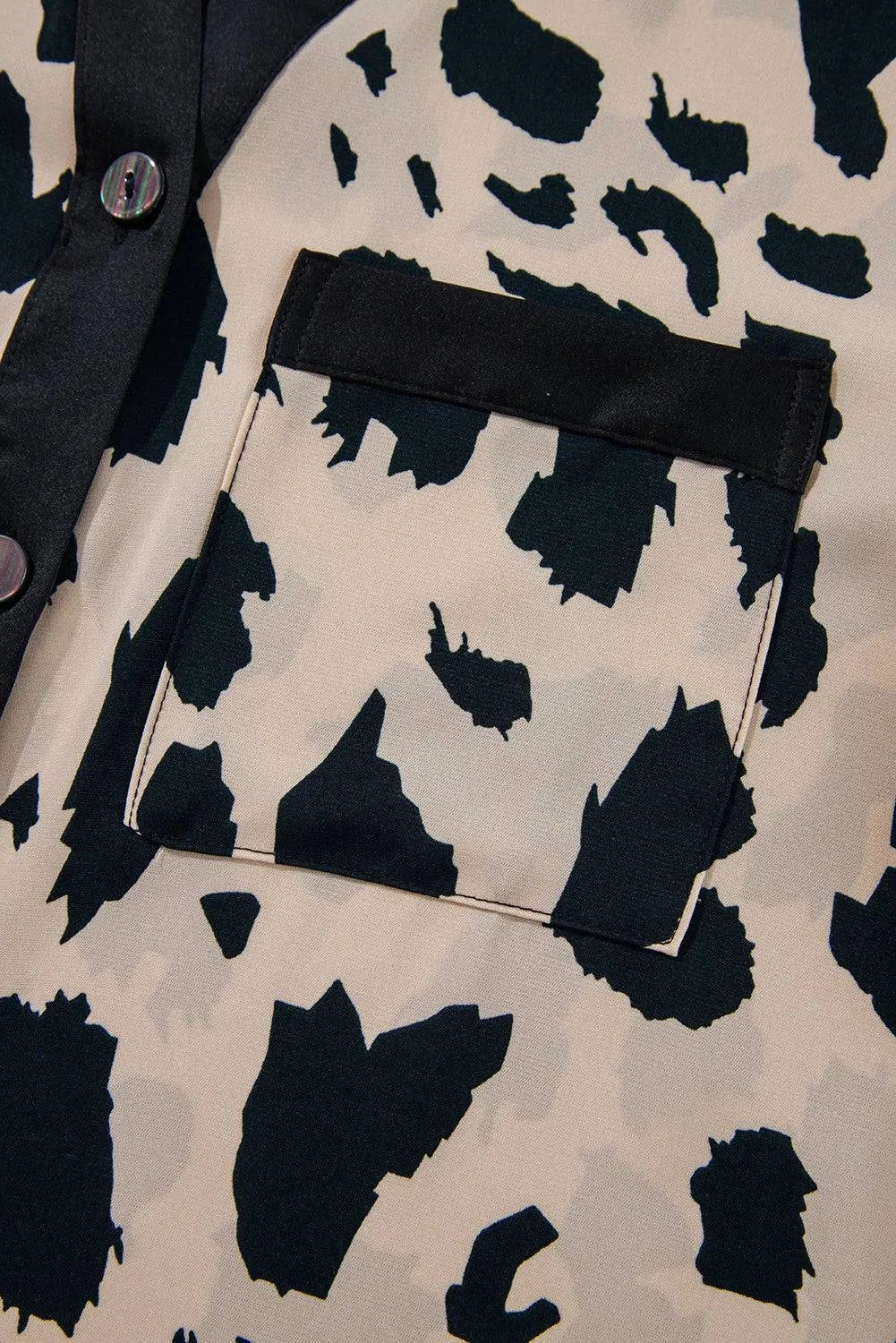 Close-up of button-up long sleeve top with black and beige abstract print pocket detail