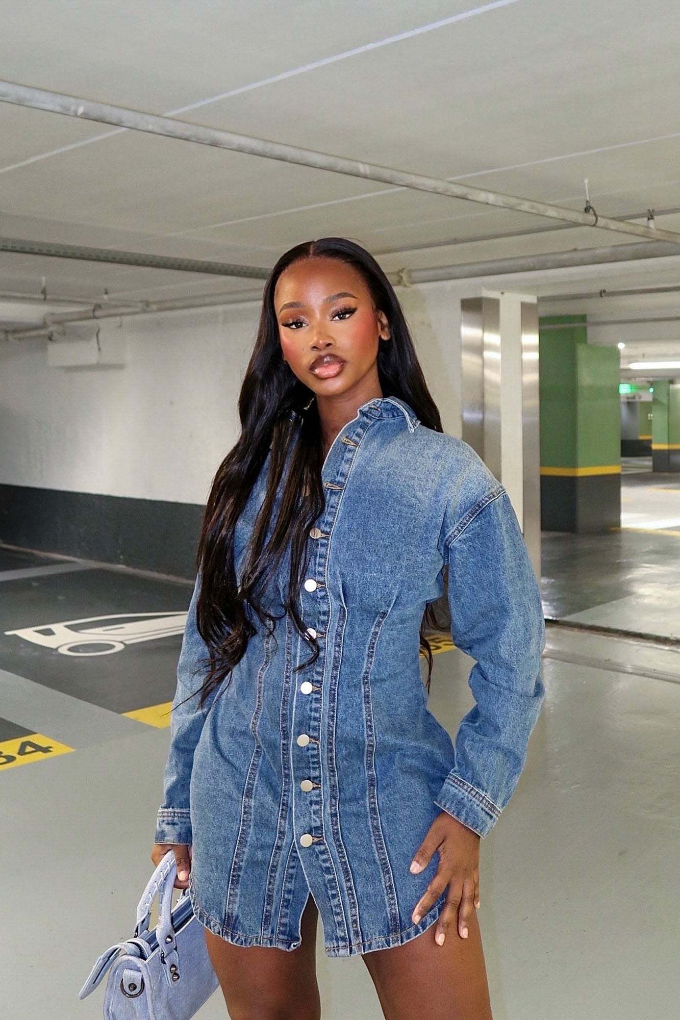Model wearing Alessandra Denim Mini Dress medium wash in parking garage