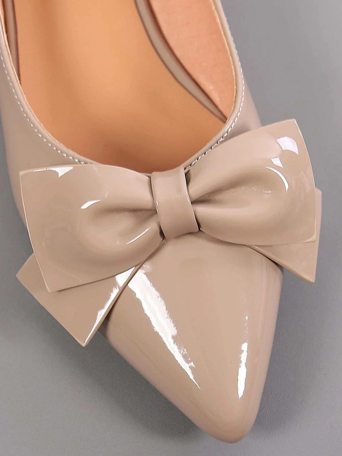 Close-up of women bow decor point toe flats in beige patent leather