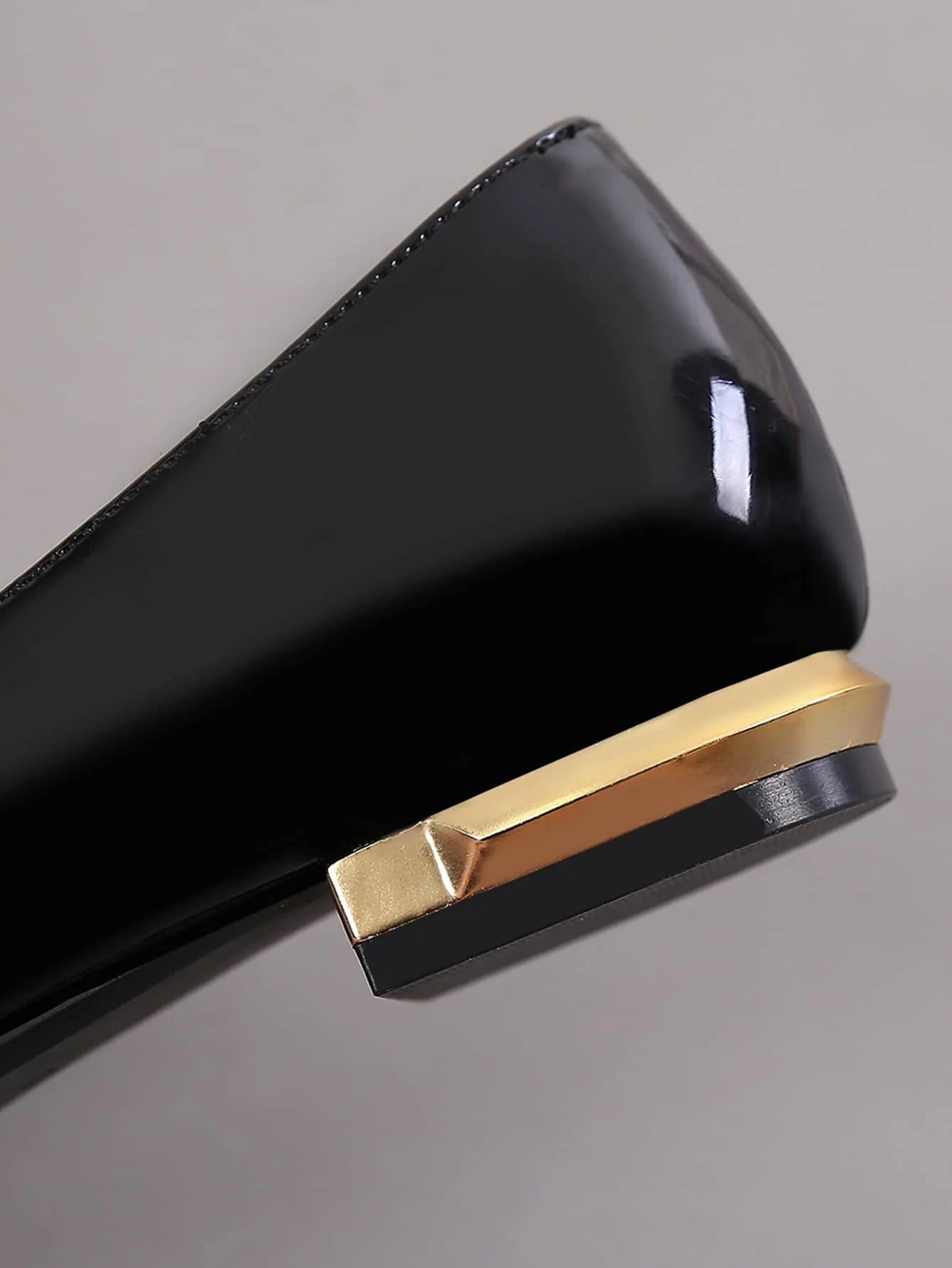 Close-up of black shiny flat shoe heel with gold accent design