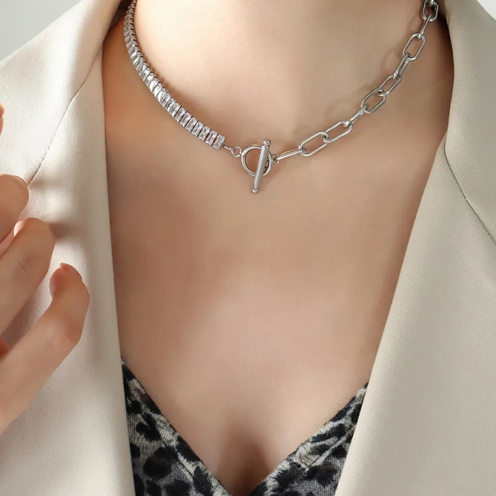Close-up of a titanium steel silver necklace with toggle clasp worn on a person's neck with beige blazer and patterned top