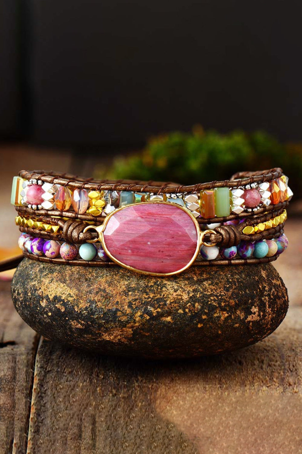 Handmade crystal beaded natural stone bracelet with colorful beads and central pink stone centerpiece on rustic background