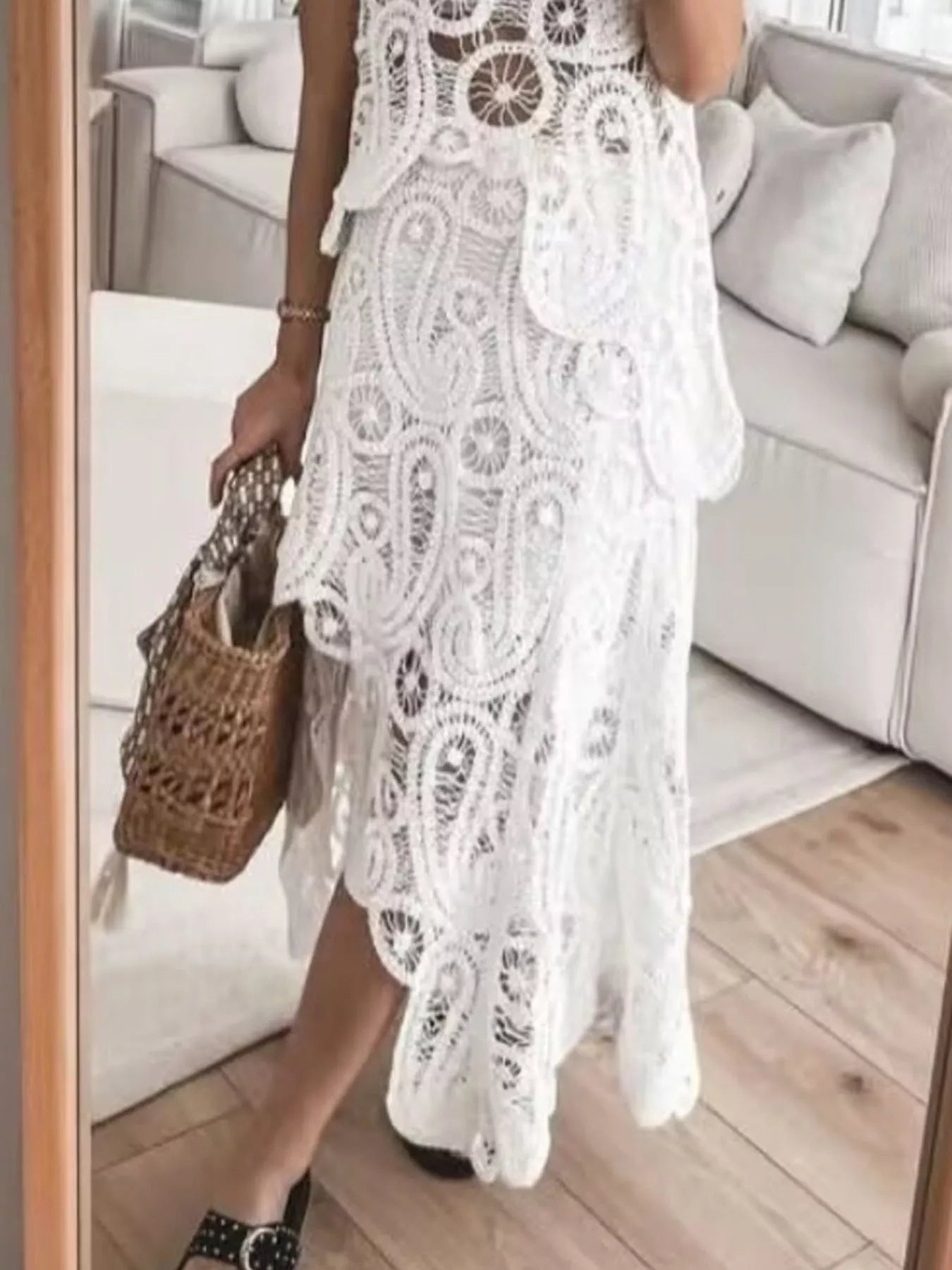 Woman wearing white openwork asymmetrical crochet sleeveless tank and skirt set with woven handbag and black shoes