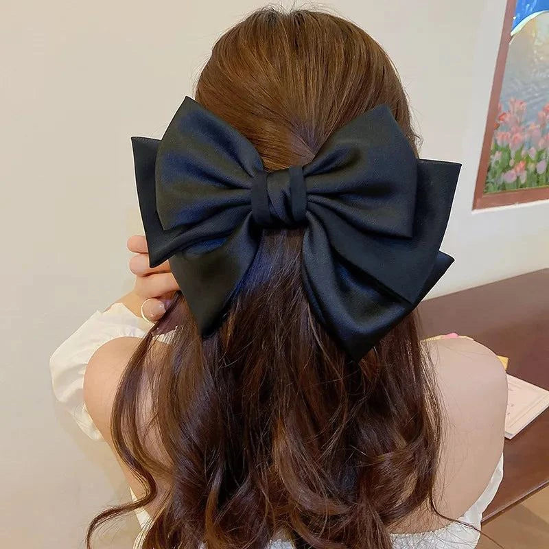Black bow cloth hair clip worn on long brown hair for stylish look
