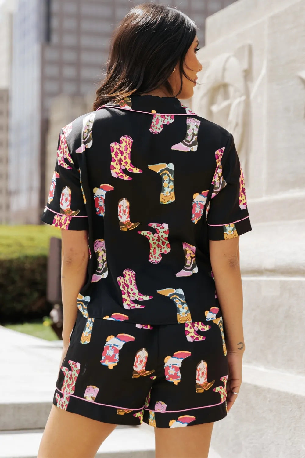 woman wearing black printed button up short sleeve top and shorts lounge set with colorful boot patterns
