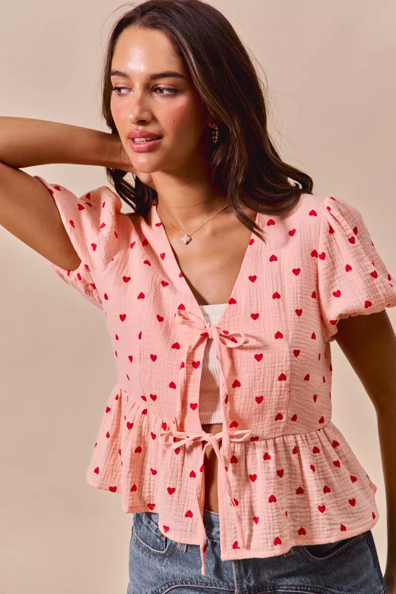 Woman wearing pink all over heart ribbon tie baby doll Valentine blouse with red heart print and puff sleeves