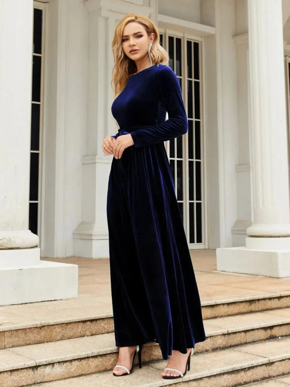 Woman wearing navy blue tie front round neck long sleeve maxi dress outdoors on steps