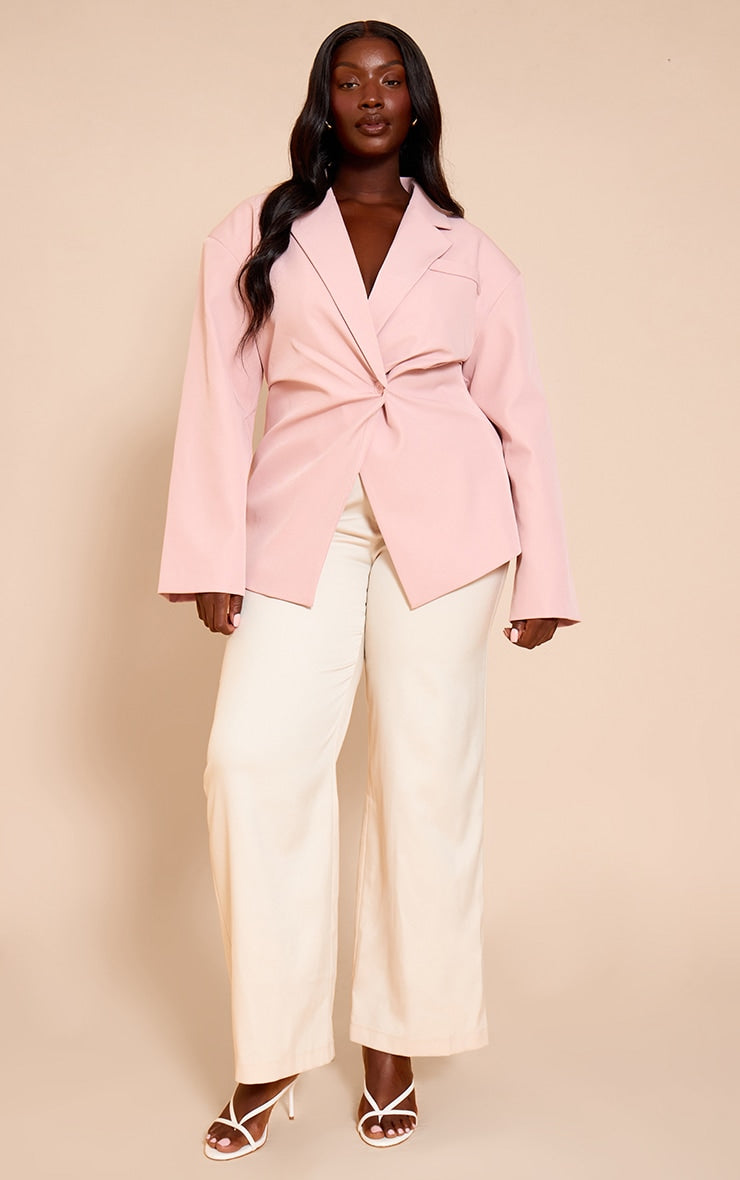 Plus pale pink tailored cinched waist blazer on plus size model paired with cream wide leg trousers and white heels