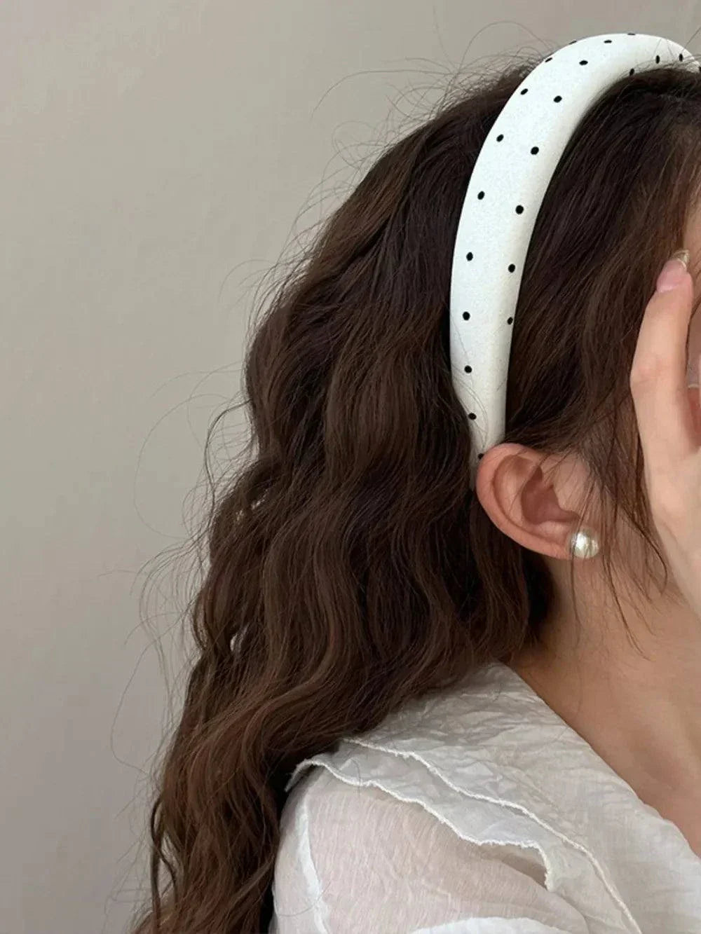 White polka dot polyester wide headband on woman with wavy brown hair