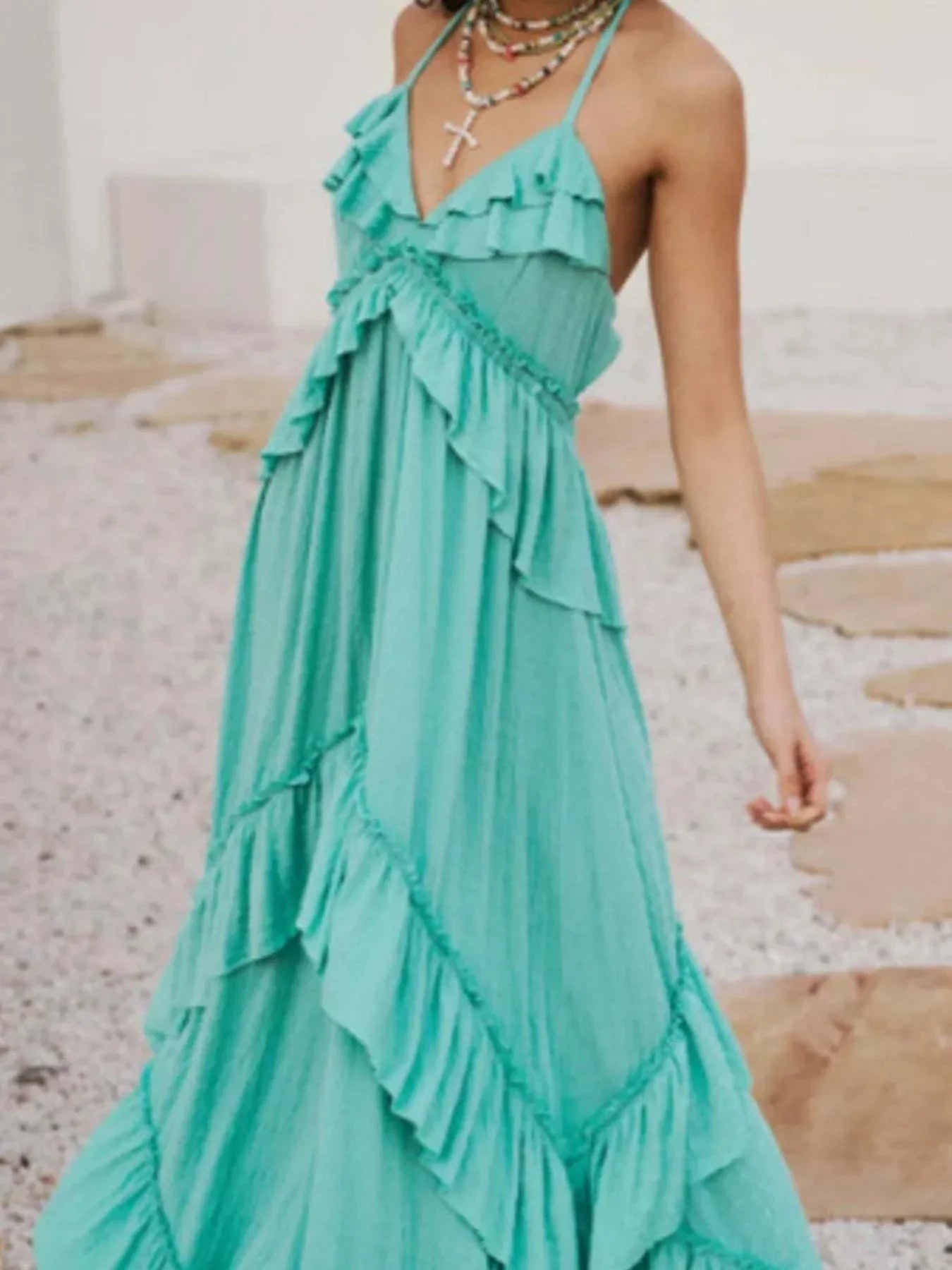 Woman wearing teal ruffled halter neck maxi dress with layered ruffles and tied straps outdoors