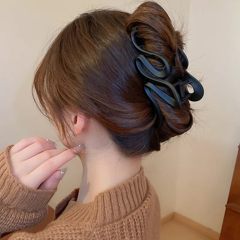 Black alloy acrylic hair claw clip holding twisted brown hair in a bun