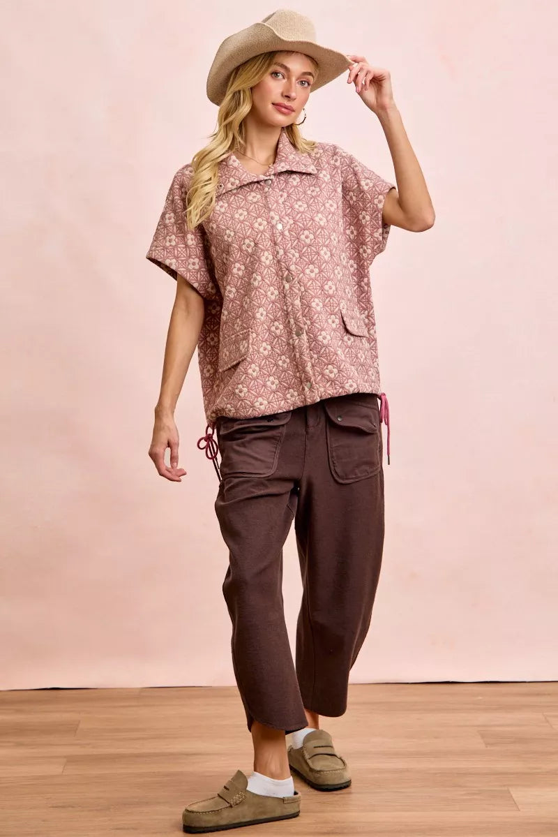 Woman wearing BiBi washed terry pants with pockets in brown paired with a patterned short-sleeve shirt and hat
