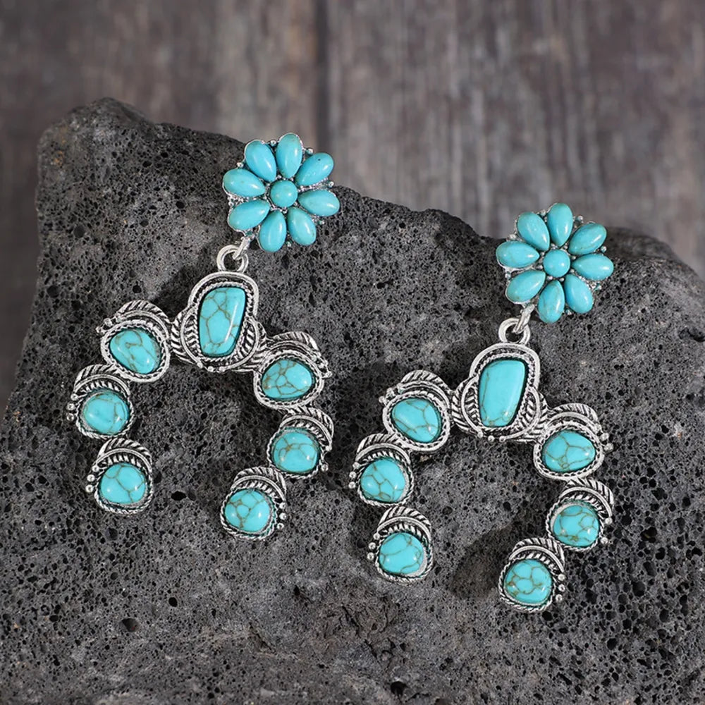 Artificial turquoise alloy dangle earrings with floral and geometric design on rock background
