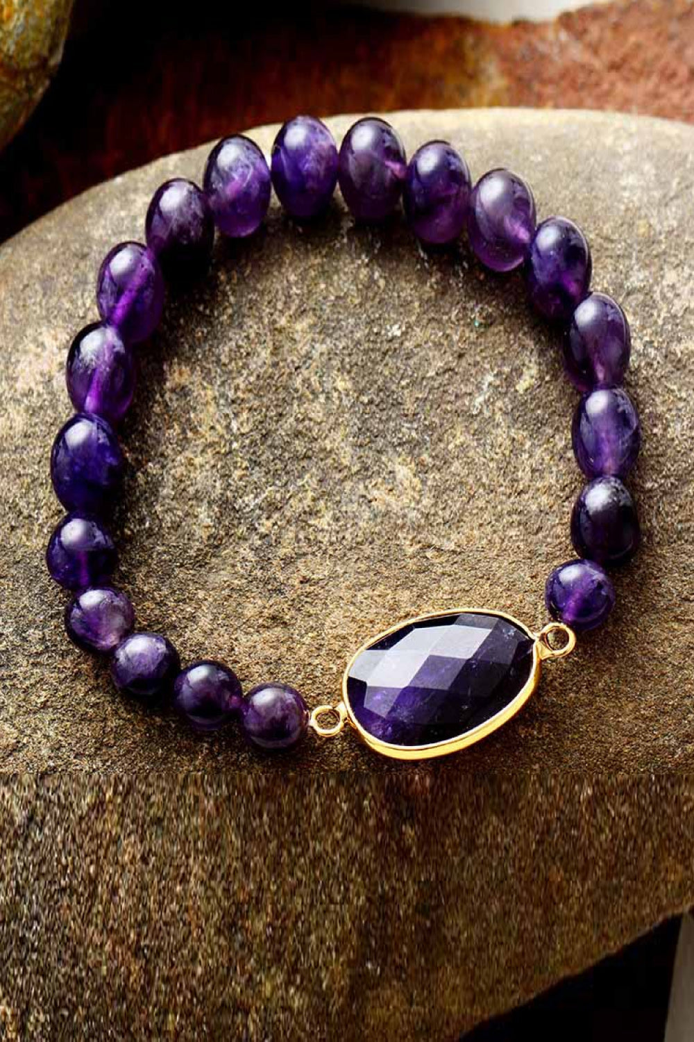 Handmade amethyst beaded bracelet with copper accents on stone background