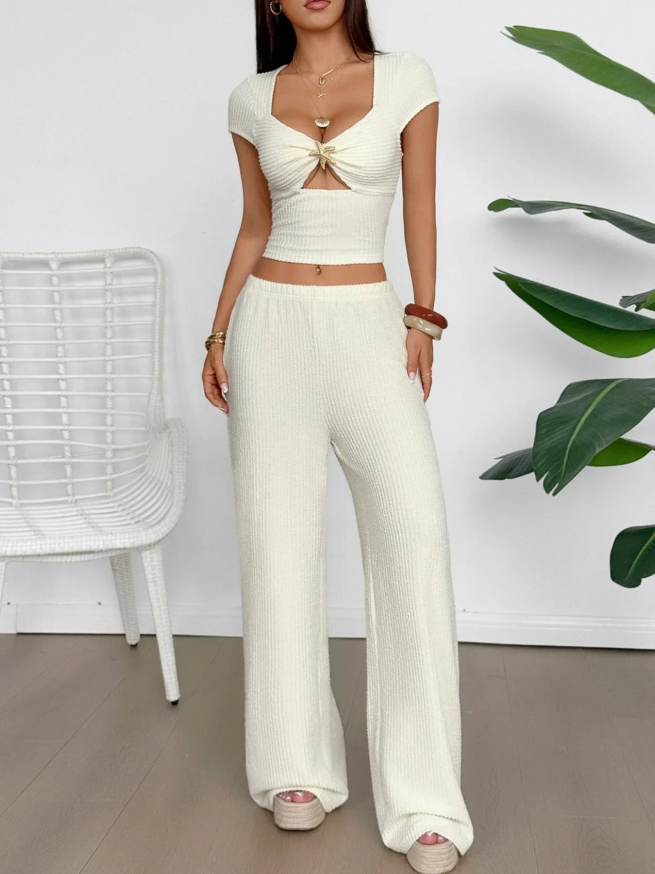 Woman wearing cream cutout short sleeve tied top and matching wide-leg pants set