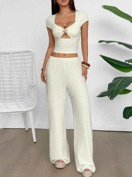 Woman wearing cream cutout short sleeve tied top and matching wide-leg pants set
