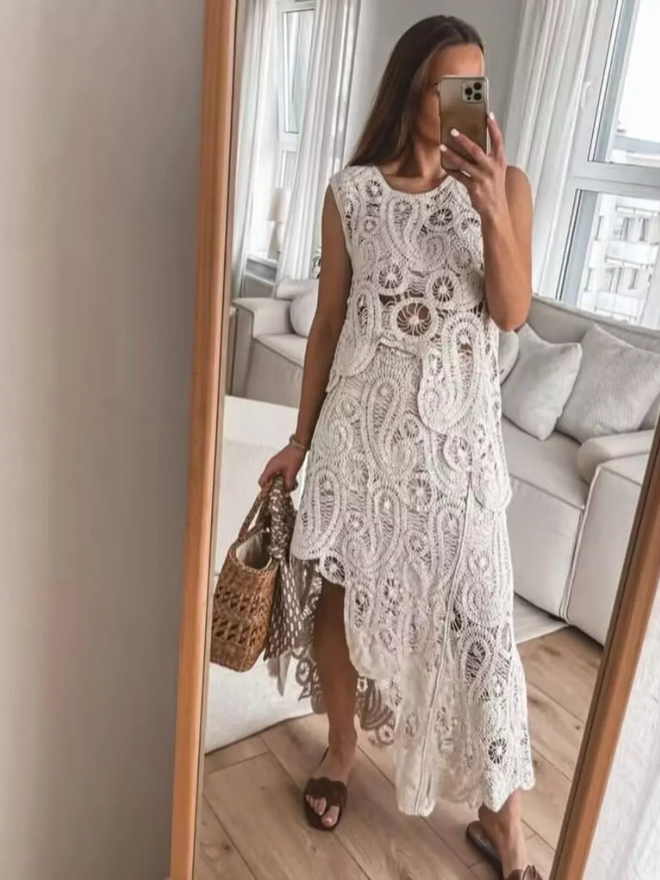 Woman wearing white crochet sleeveless tank and asymmetrical skirt set with openwork design.