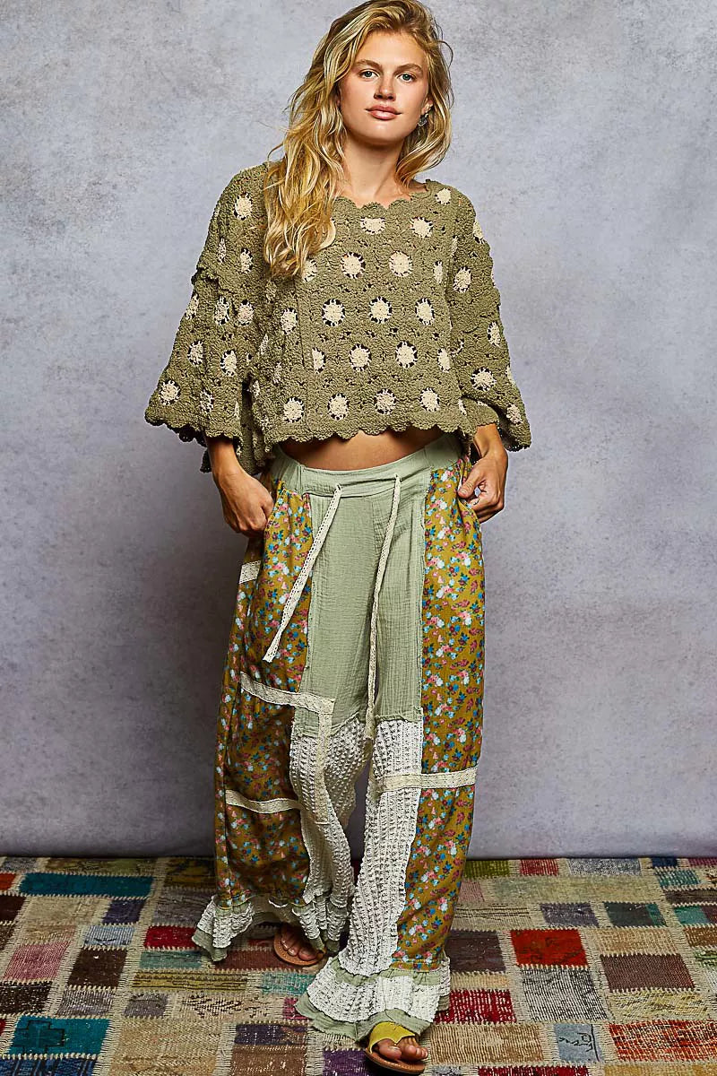 Woman wearing POL contrast crochet cropped knit top with floral patterned wide-leg pants against gray background