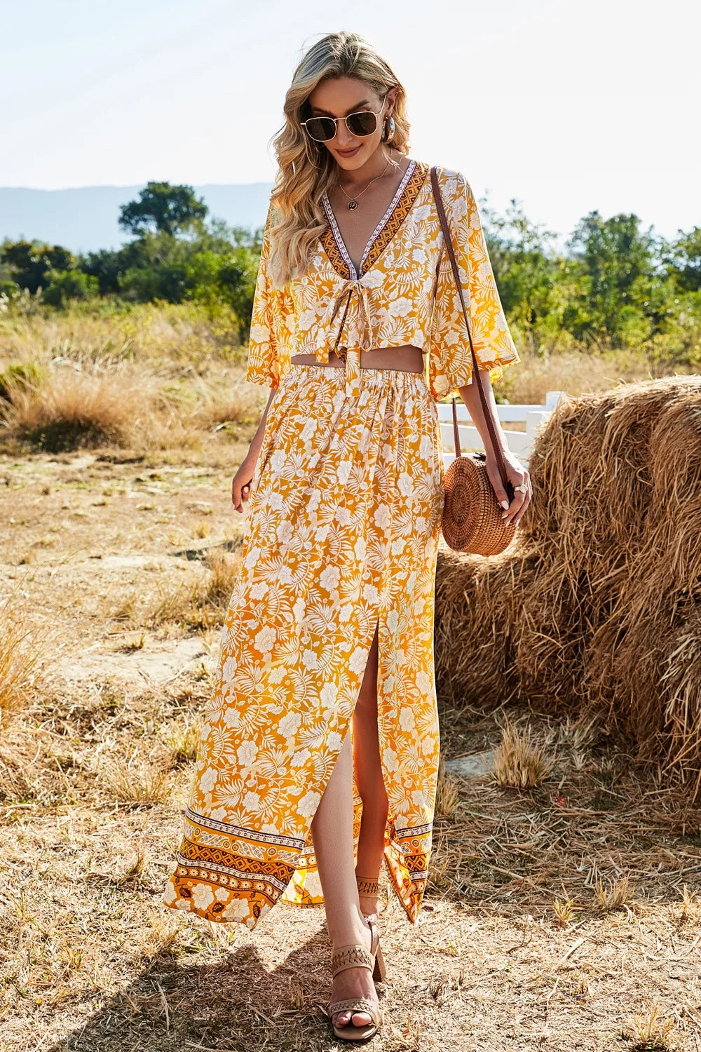 Woman wearing yellow printed half sleeve top and slit skirt set in outdoor rustic setting