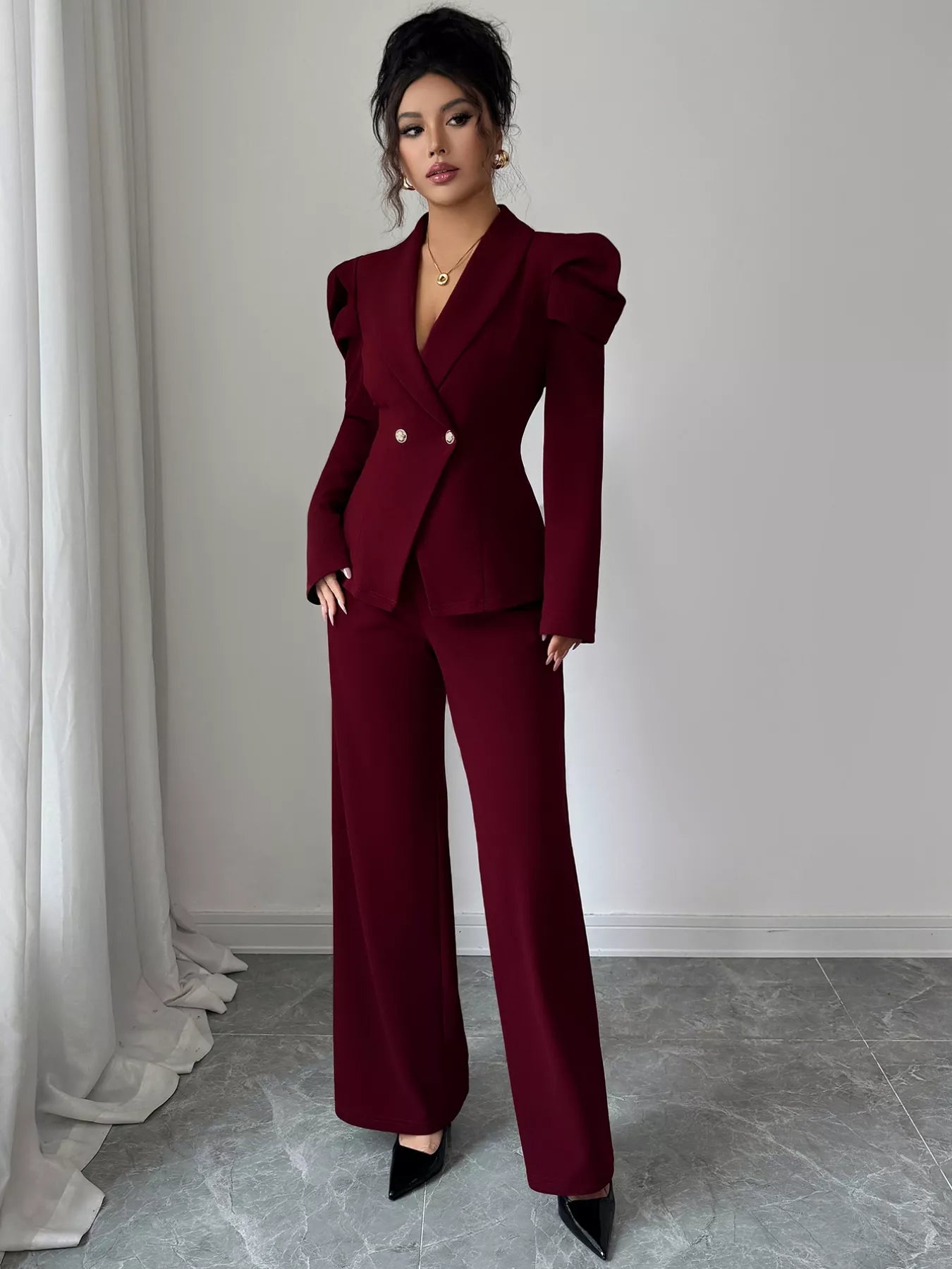 Woman wearing burgundy double-breasted blazer and pants suit set with structured shoulders and gold buttons