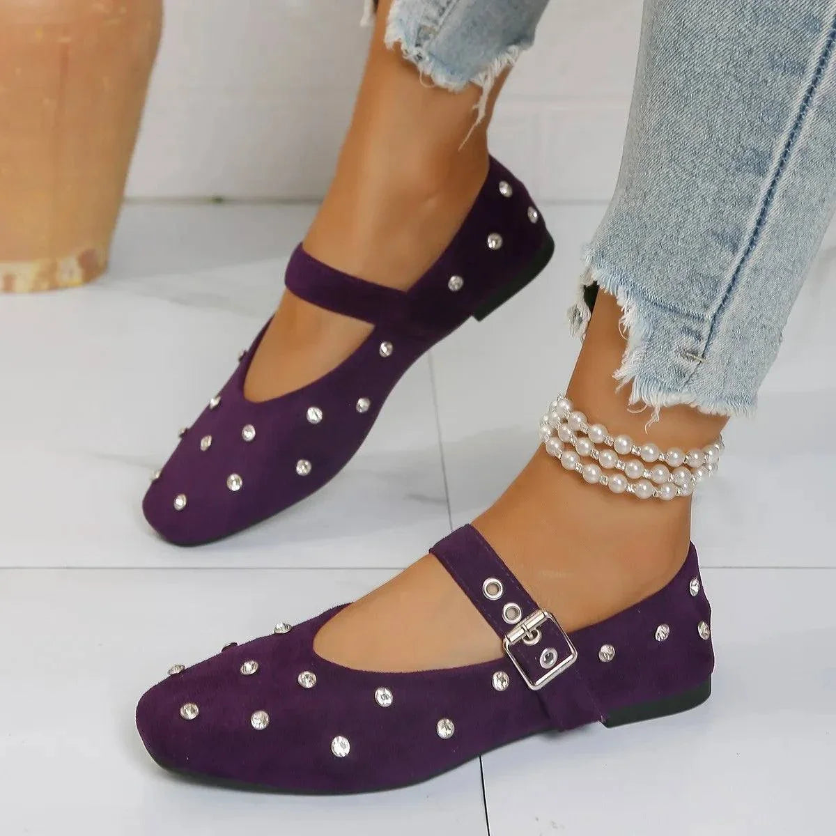 Purple rhinestone buckle flat Mary Jane loafers on feet with pearl anklet and ripped jeans