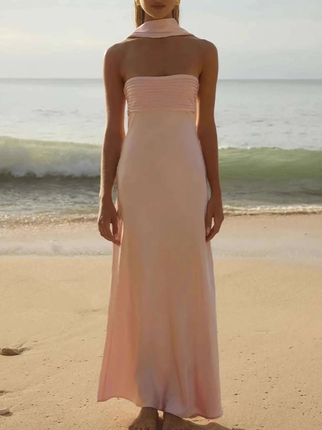 Elegant blush pink Tube Mermaid Maxi Dress with strapless design and fitted bodice on beach background