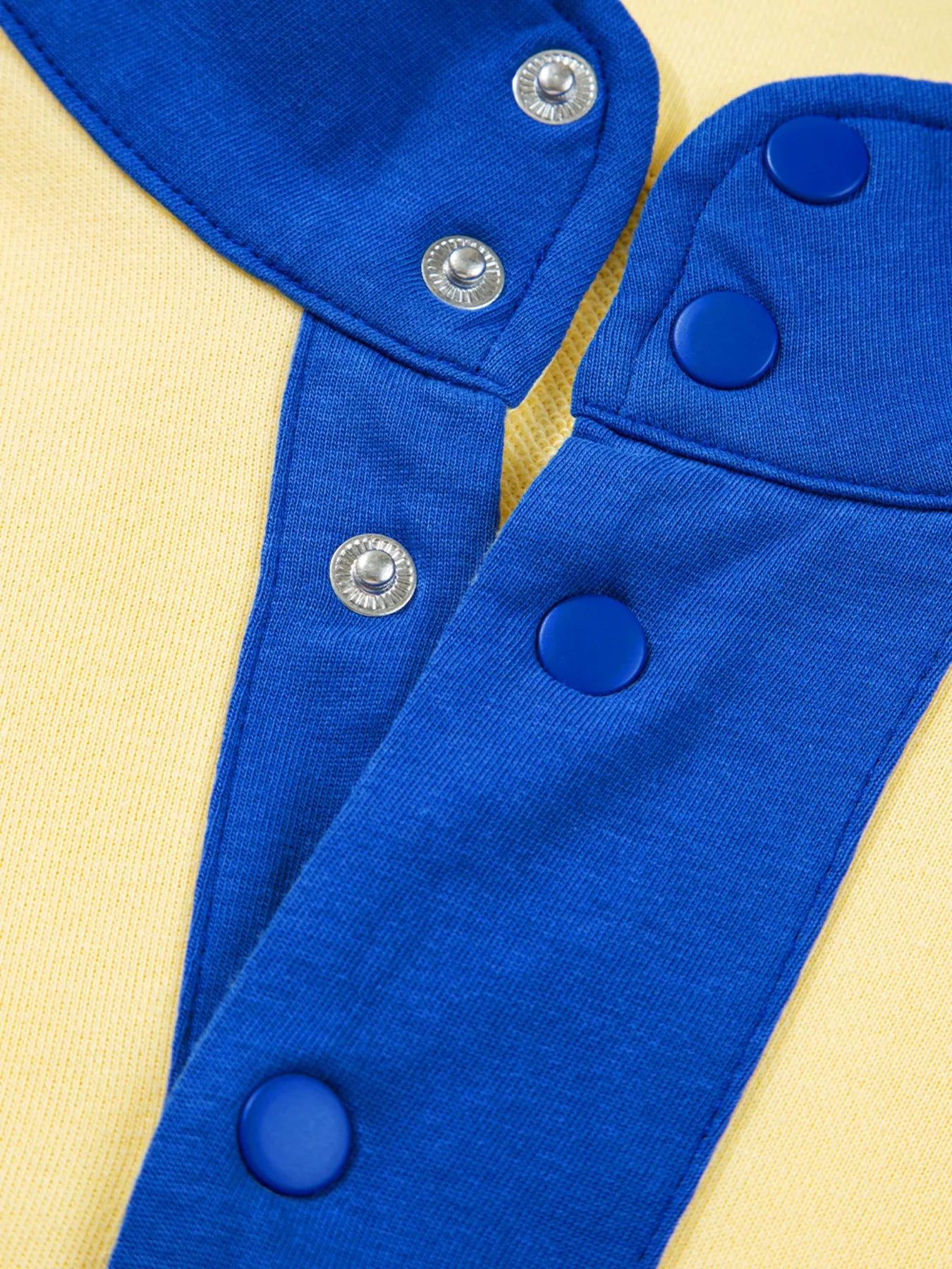 Close-up of blue and yellow color block patchwork half button top with snap buttons and fabric texture detail