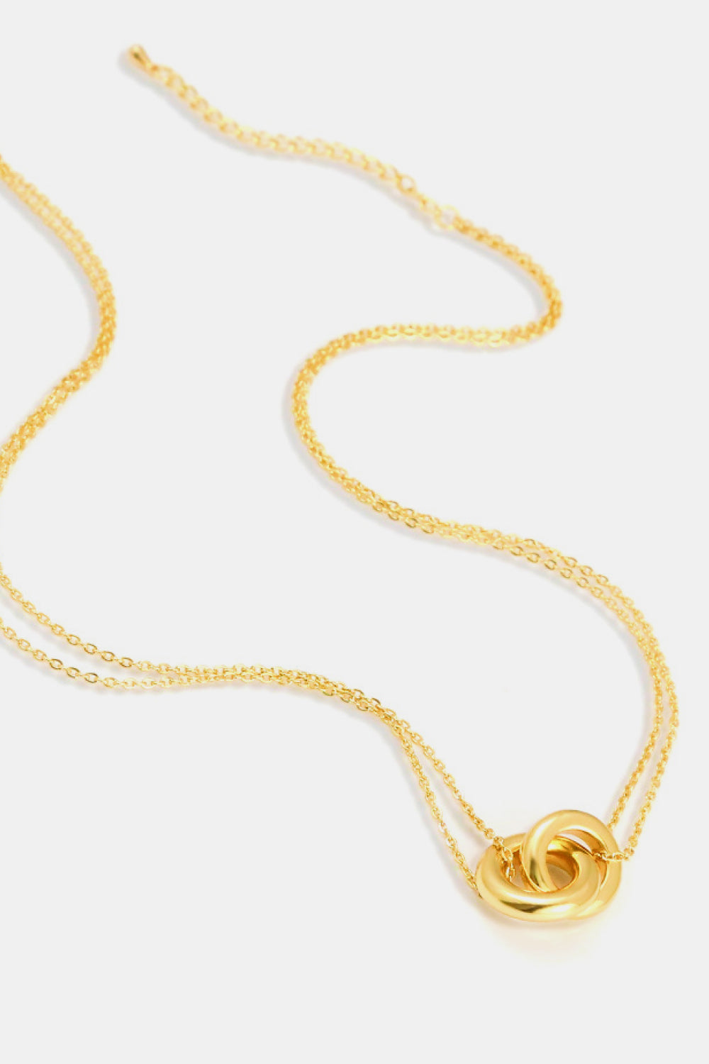 Gold linked ring pendant chain necklace flat lay on white background