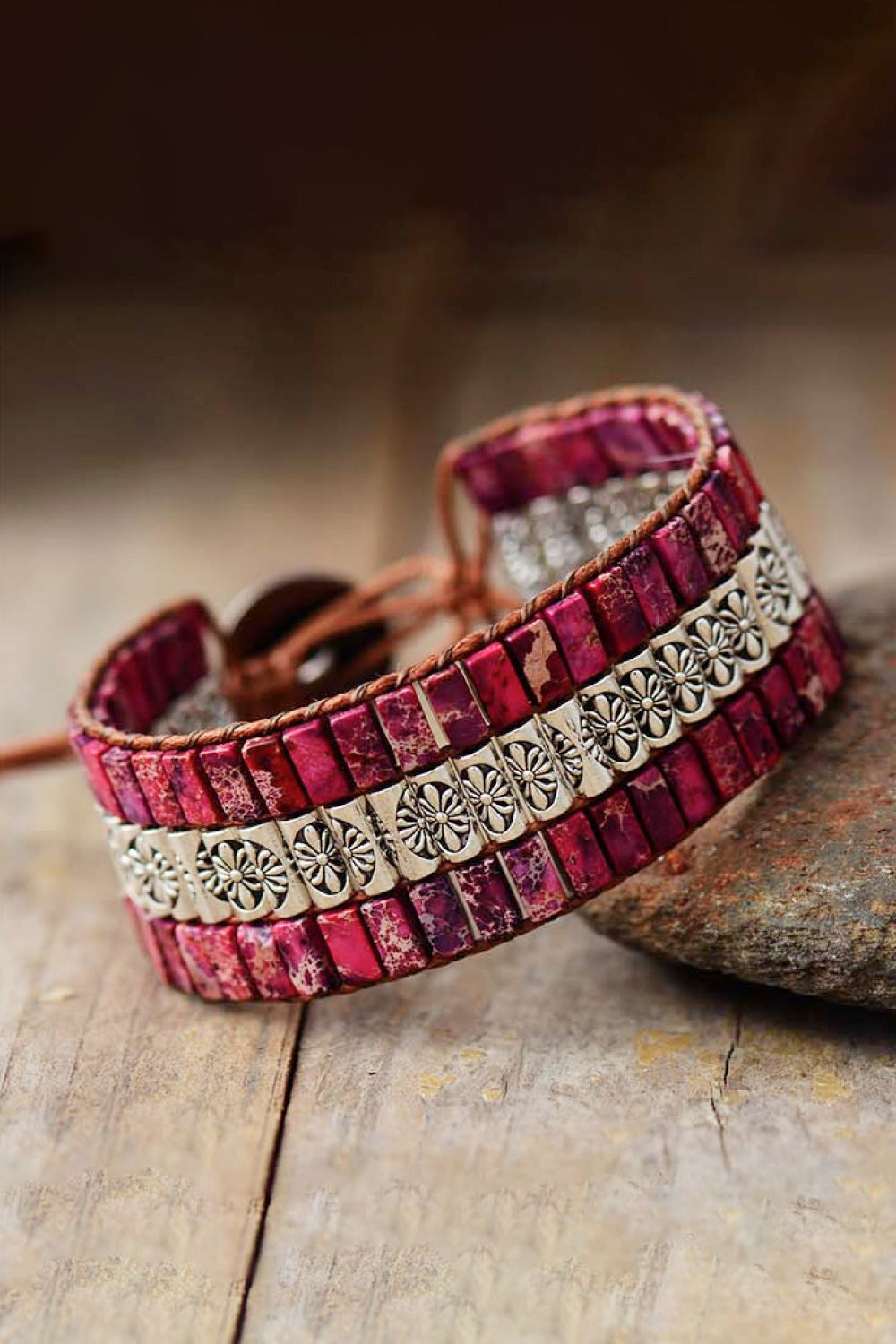 Handmade triple layer natural stone bracelet with red stones and silver floral accents on wooden surface