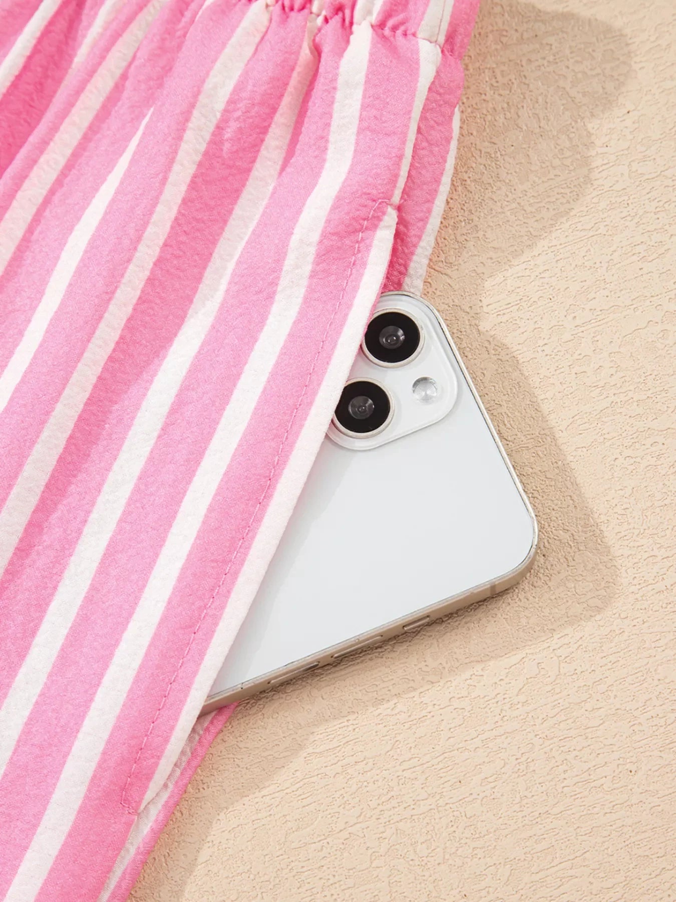 Close-up of pink and white stripe buttoned front sleepwear pants with elastic waistband and phone pocket detail