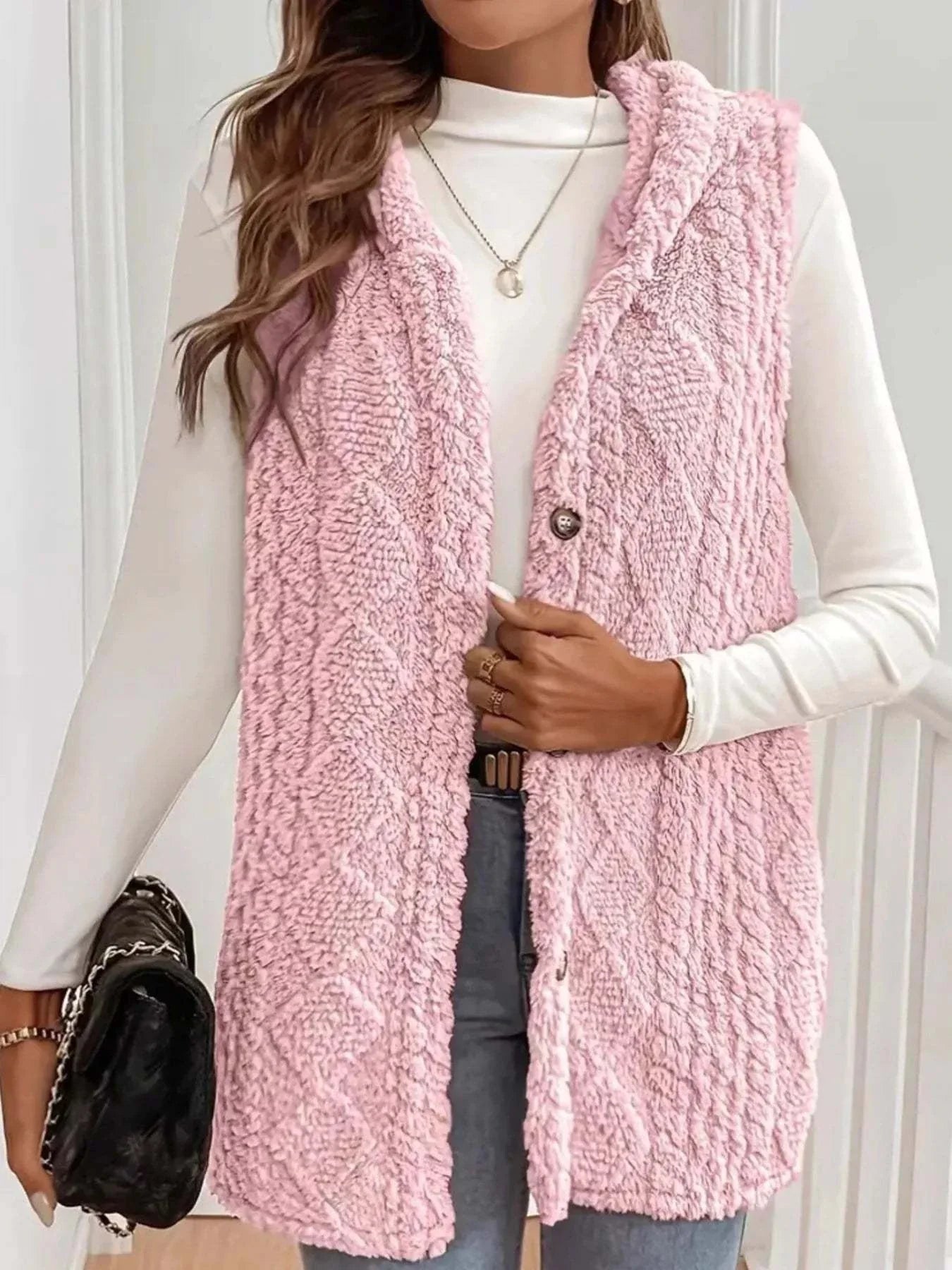 Pink button up plush hooded vest coat worn over white long sleeve top with textured polyester fabric