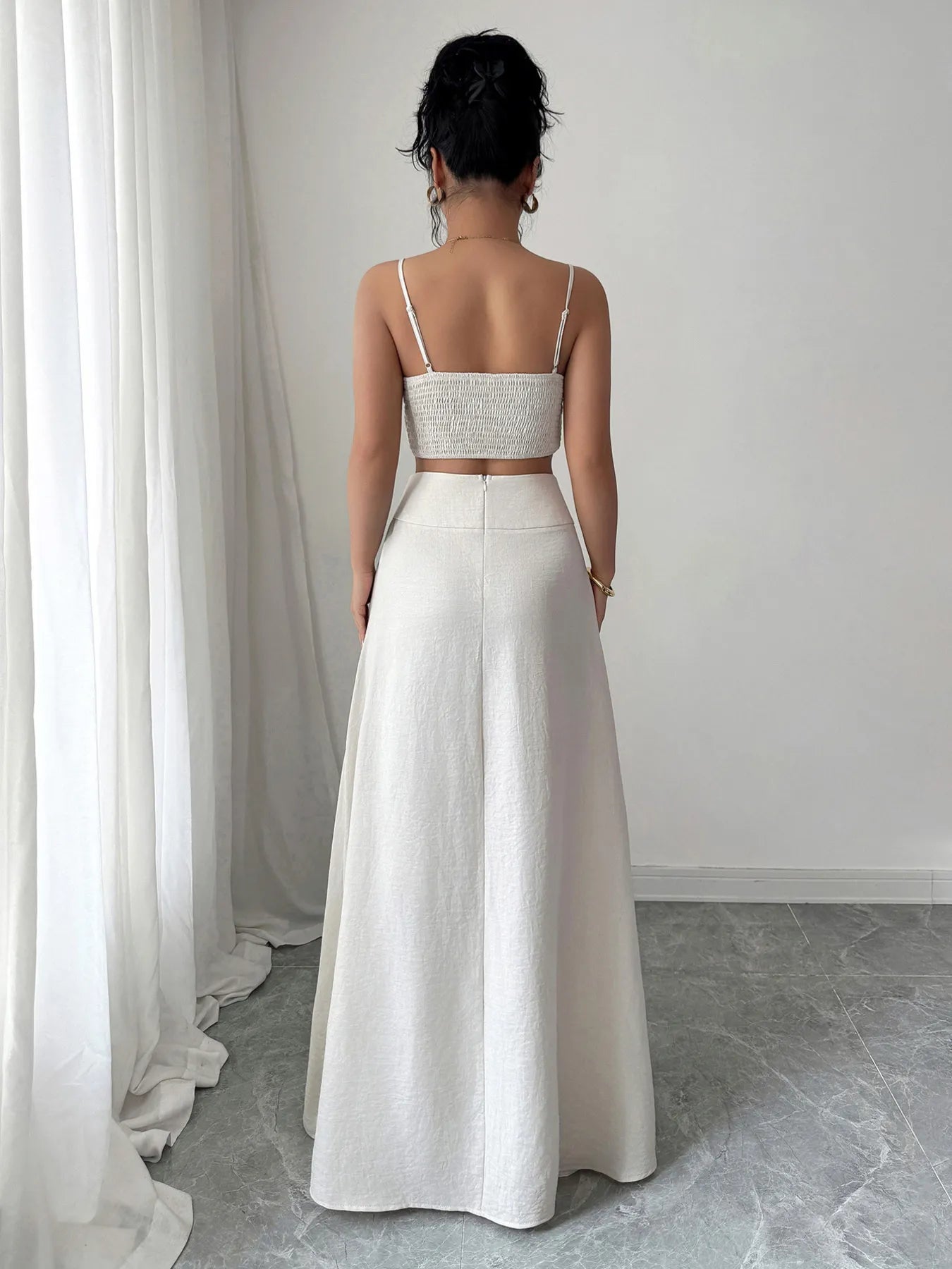 Woman wearing white square neck cami and maxi skirt set with ruched smocked top and zipper back, standing indoors.