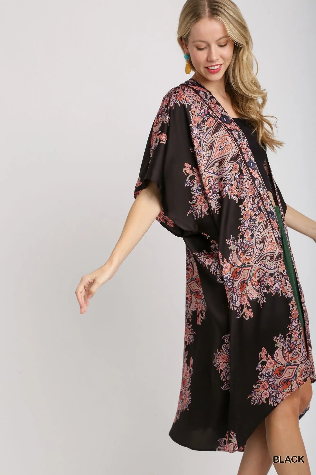 Woman wearing Umgee Satin Border Print short sleeve open front kimono in black paisley and floral pattern