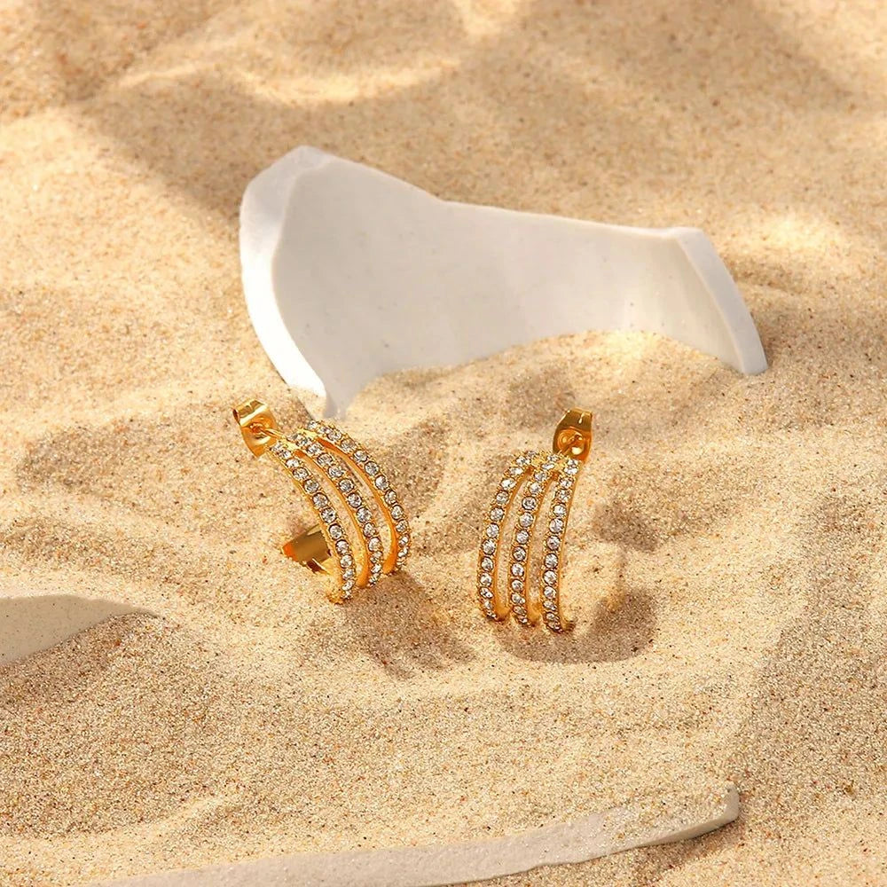 Gold-plated stainless steel C-hoop earrings with zircon inlay placed on sand