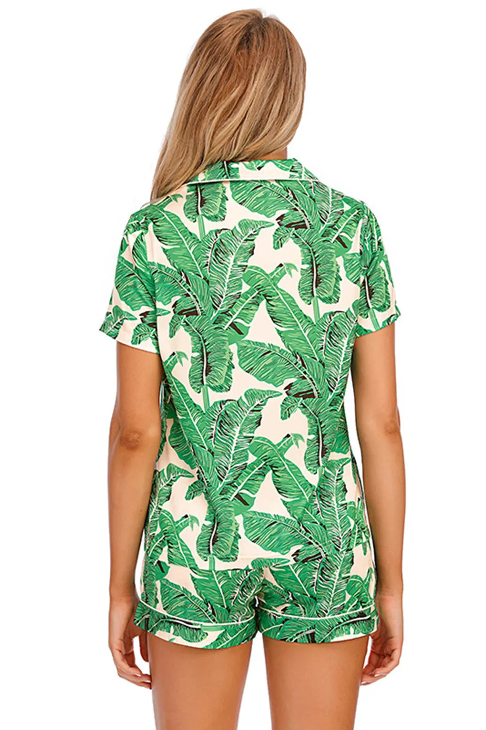 Back view of woman wearing printed button up short sleeve top and shorts lounge set with green leaf pattern