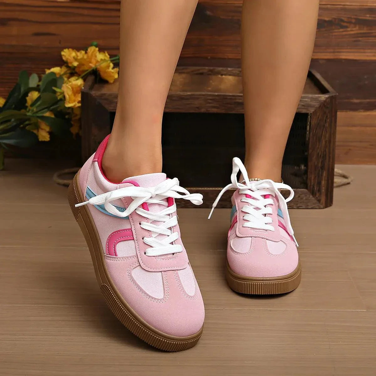 Pink lace up platform sneakers with white laces and rubber soles on wooden floor