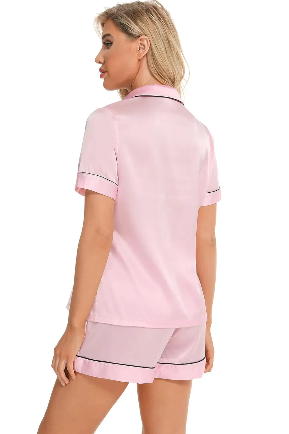 Woman wearing pink printed button up short sleeve top and shorts lounge set from back view