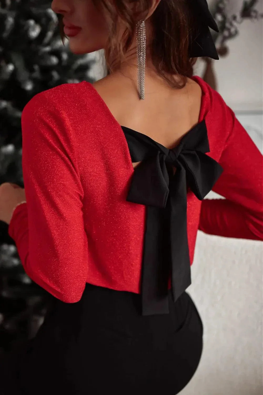Woman wearing red Bowknot V-Neck long sleeve blouse with black bow back detail and dangling earrings