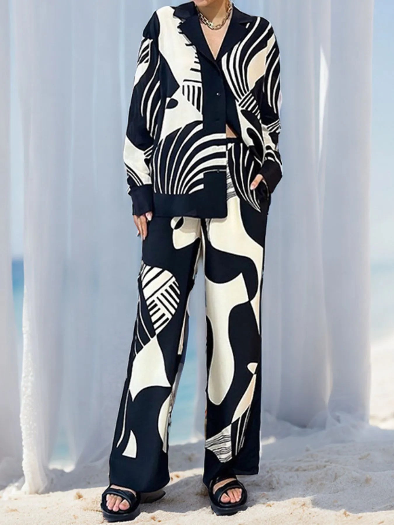 Printed long sleeve shirt and pants set with black and white abstract pattern, buttoned top, and pocketed pants.