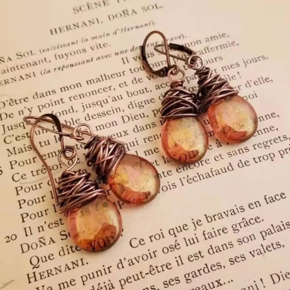 Alloy gemstone drop earrings with teardrop-shaped amber stones and wire wrap detail on rustic background text.
