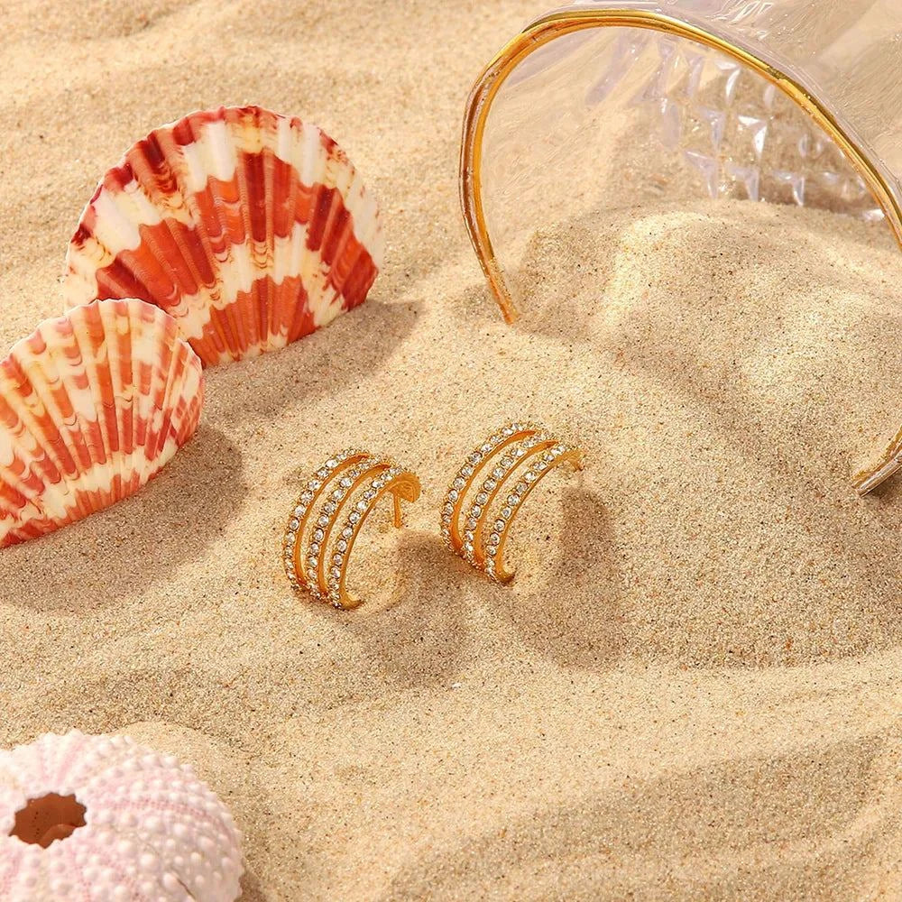 Gold-plated stainless steel zircon inlaid C-hoop earrings on sandy beach with seashells